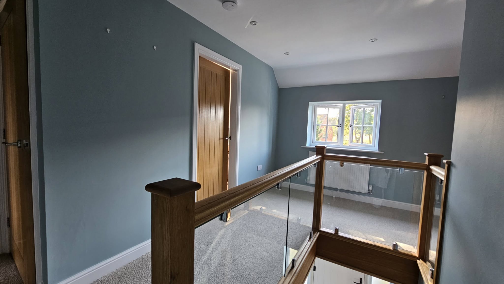 Landing after, blue-grey walls around the glass balustrade