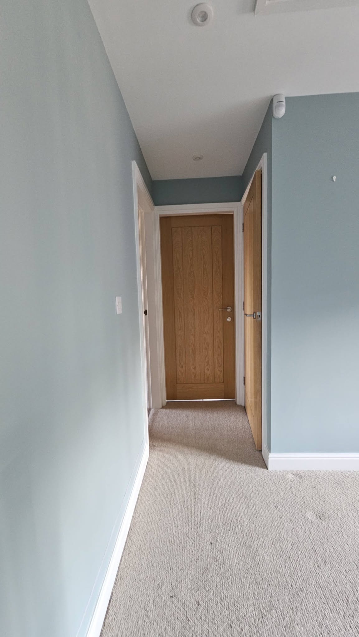 The same hallway after, painted blue-grey with fresh white skirting