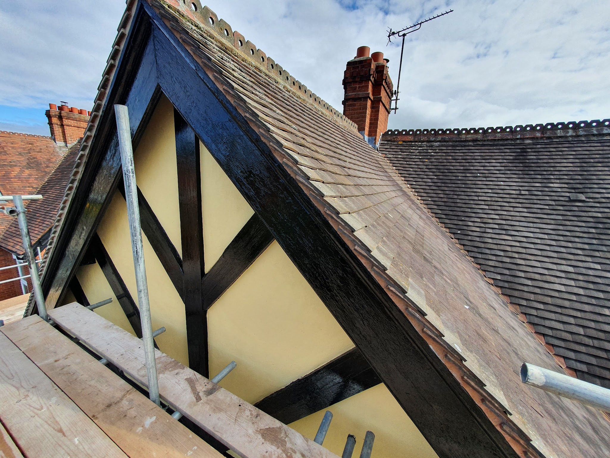 Tudor-style gable painted black and cream, seen from the scaffold
