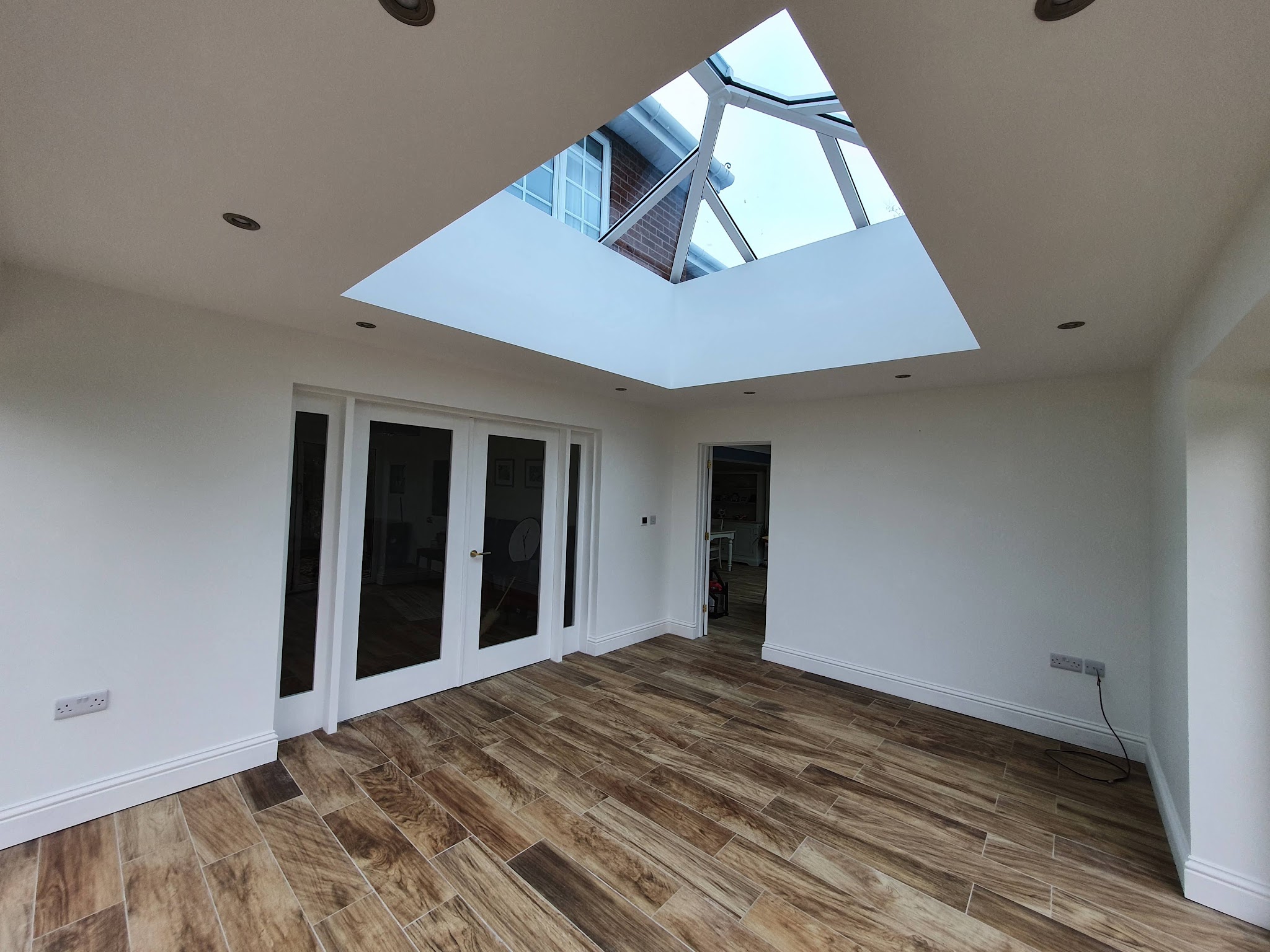 Bright white garden room with a roof lantern and wood-effect floor
