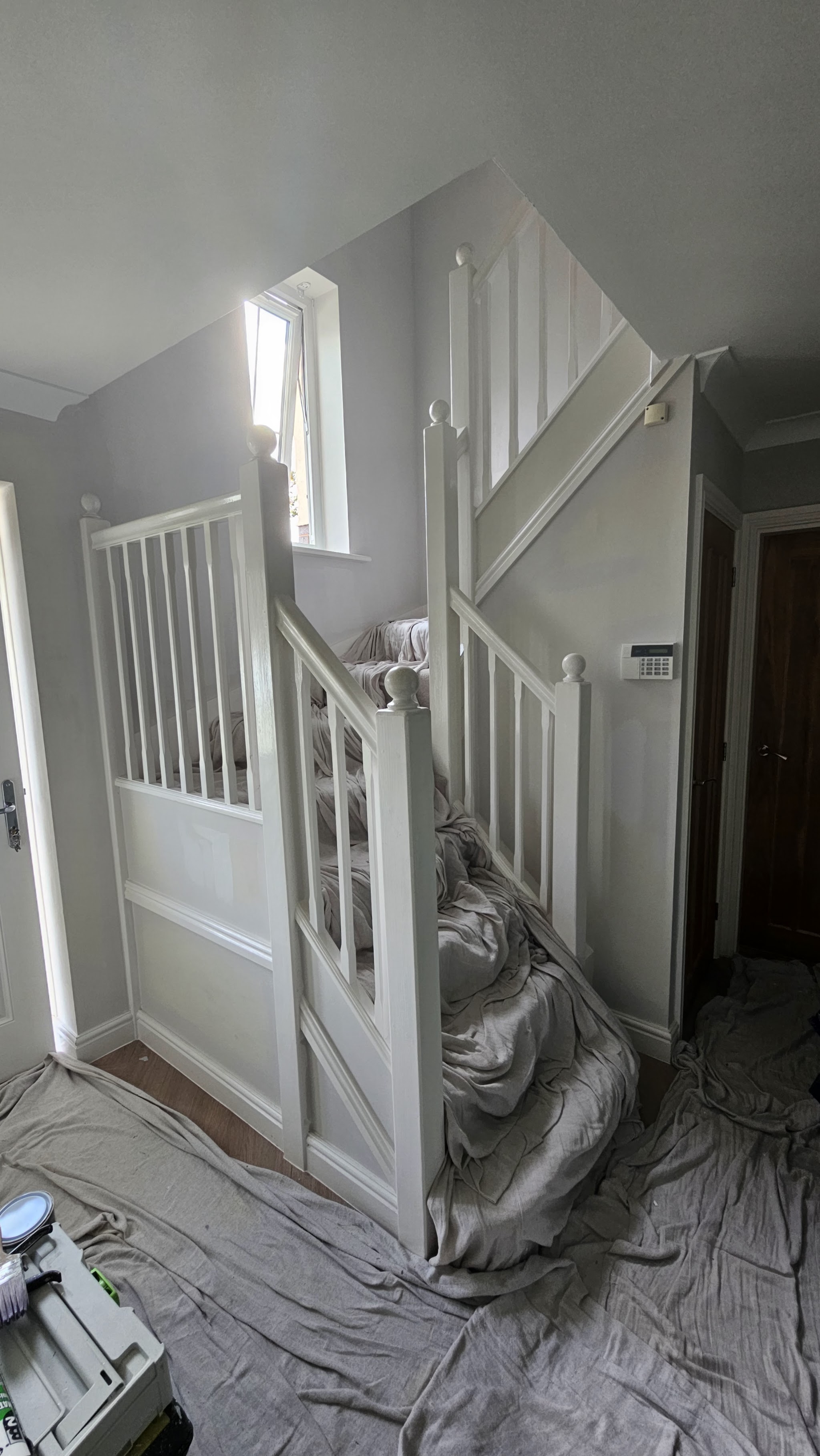 White staircase and landing being painted, with the carpet protected